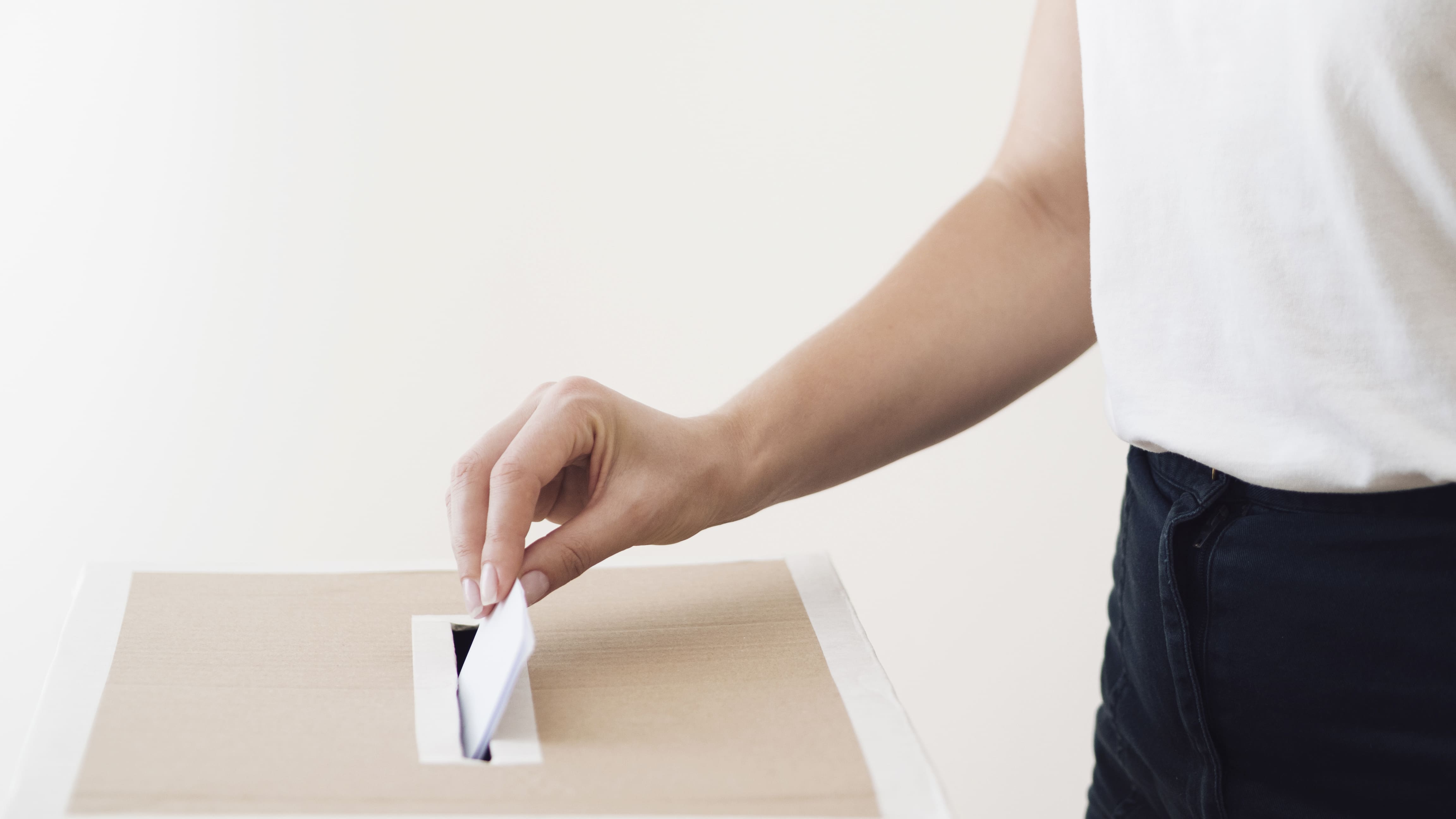 side view person placing ballot in election box 1